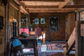 A rustic wooden interior with a dining area, a staircase, and a large painting on the wall. - Arthaus Megeve (Demi-Quartier)