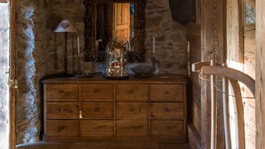 A rustic wooden cabin interior with a stone wall, wooden dresser, and a mounted ram's head. - Arthaus Megeve (Demi-Quartier)