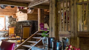 A rustic interior with a wooden staircase, a large metal tub, and a red chair. - Arthaus Megeve (Demi-Quartier)