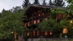 A rustic wooden cabin with multiple windows and balconies, surrounded by lush greenery. - Arthaus Megeve (Demi-Quartier)