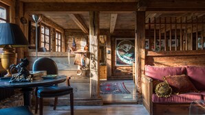 A wooden cabin interior with a round table, chairs, a sofa, and a fireplace. - Arthaus Megeve (Demi-Quartier)