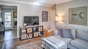 Ein Wohnzimmer mit Sofa, Fernseher, Lampe, einer Uhr und einer Wand mit einem Motivationsspruch.