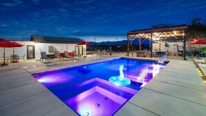 A swimming pool with a built-in jacuzzi, surrounded by outdoor seating and a covered area. - Modern Ranch House~Great for Big Groups! Salt Water Pool + Spa  (Desert Hot Springs)