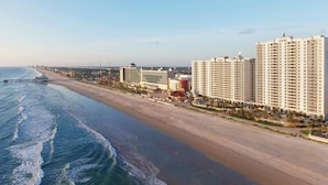Un hotel costero con varias edificaciones de gran altura, una playa y un muelle.