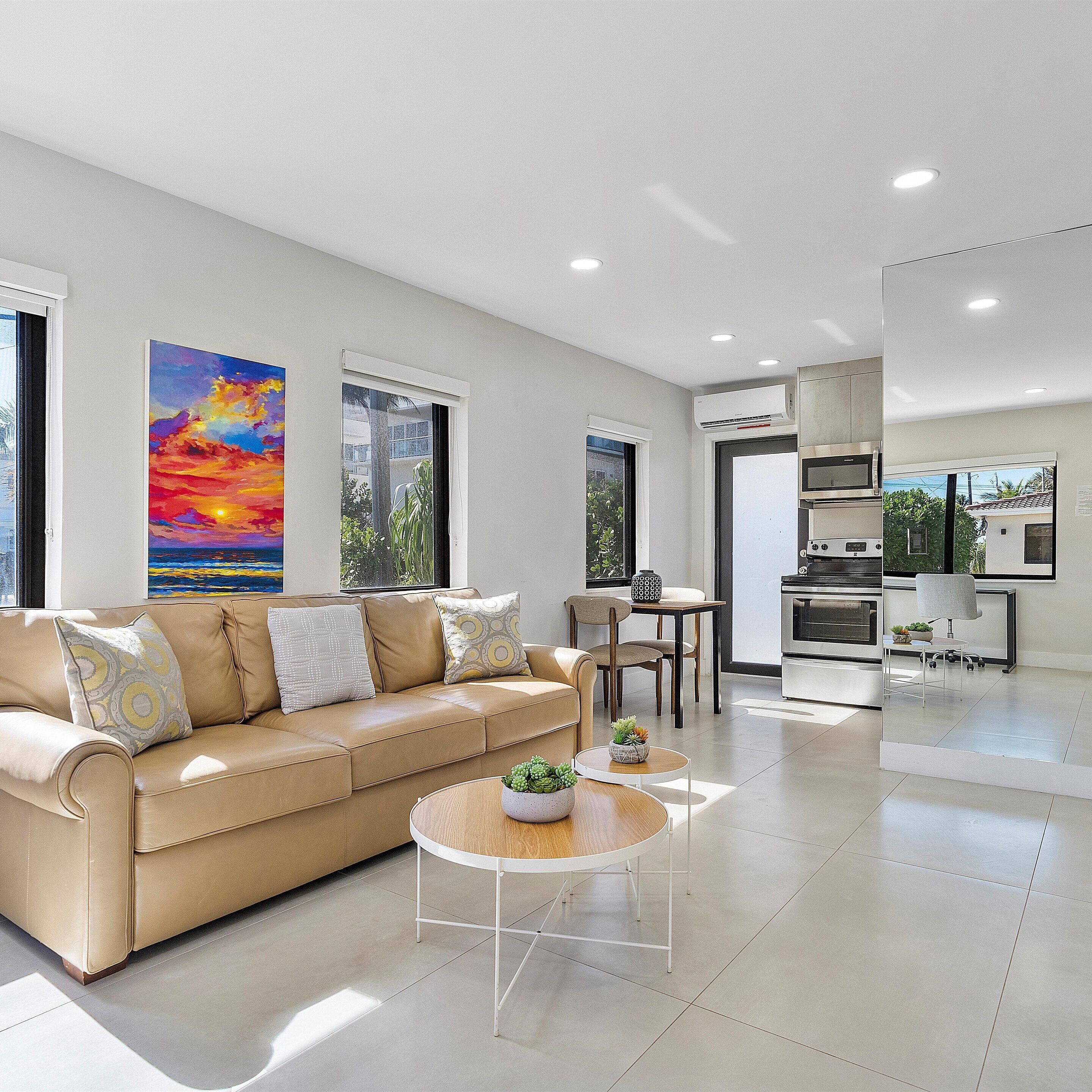 A modern living room with a beige sofa, a round coffee table, and a dining area with a small table and chairs.