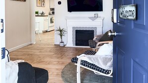 Una sala de estar con chimenea, un sofá, un televisor y una puerta decorada con un girasol.