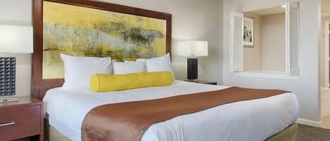 A hotel room with a large bed, a bedside table, a lamp, and a painting on the wall.