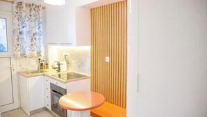A compact kitchen with a sink, stove, and a small round table. - 350m from museum of Acropolis a cozy & quit house (Αθήνα)