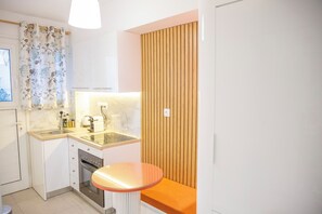 Una cocina pequeña con un lavamanos, estufa y una mesita redonda.