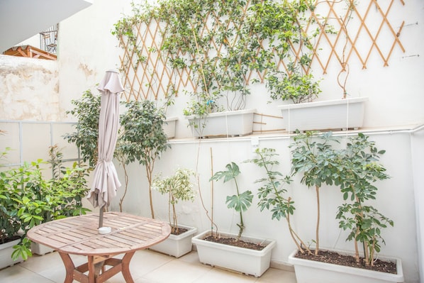 A patio with a table, potted plants, and a climbing vine wall.