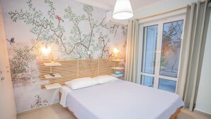 A bedroom with a bed, bedside tables, a wall mural, and a window with curtains. - 350m from museum of Acropolis a cozy & quit house (Αθήνα)