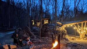 A rustic cabin with a fire pit and a covered seating area.
