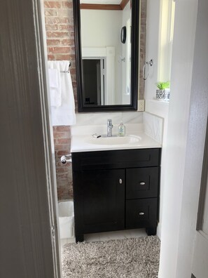 Une salle de bain avec un lavabo blanc, un meuble-lavabo noir et un grand miroir.