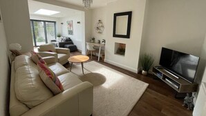 A modern living room with a sofa, coffee table, TV, and decorative items. - 3 By The Sea, Ground Floor Apartment By The Sea (Worthing)