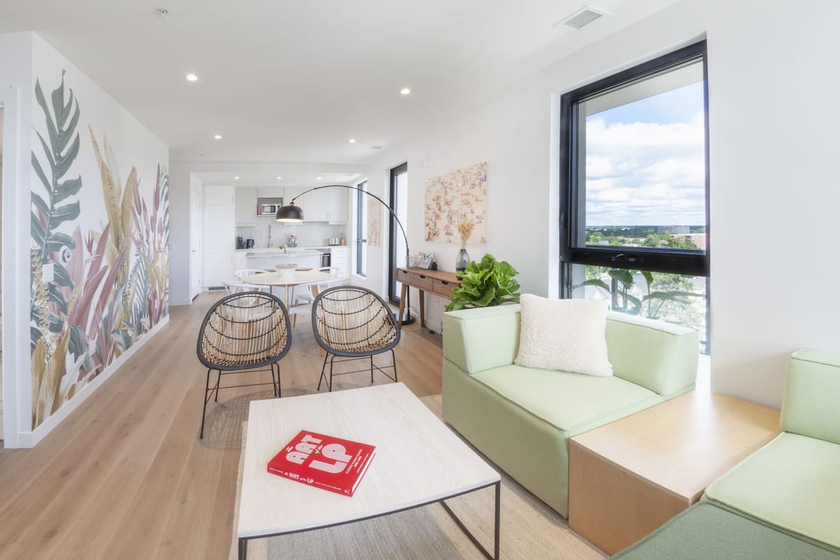 A modern living room with a sofa, a coffee table, and a dining area with chairs.
