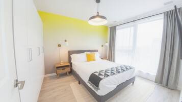 A modern bedroom with a bed, bedside tables, and a large window with curtains.
