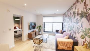 A modern living room with a sofa, a coffee table, a TV, and a dining area with a chair and table.