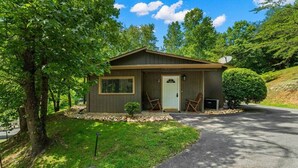 A small, single-story cabin with a front door, two rocking chairs, and a small garden area. - Pigeon Forge Getaway Near Dollywood / LeConte / The Island (Pigeon Forge)