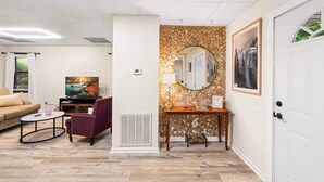 A living room with a sofa, a TV, a coffee table, a chair, a fireplace, a mirror, and a door. - Pigeon Forge Getaway Near Dollywood / LeConte / The Island (Pigeon Forge)