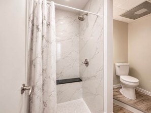 Ein Badezimmer mit Dusche, Toilette und Marmorwänden.
