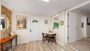 A room with a wooden floor, a white door, a dining table with chairs, and a mirror on the wall. - Pigeon Forge Getaway Near Dollywood / LeConte / The Island (Pigeon Forge)