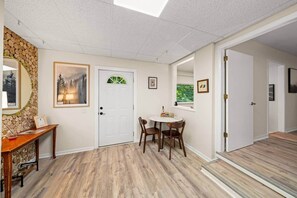A room with a wooden floor, a white door, a dining table with chairs, and a mirror on the wall. - Pigeon Forge Getaway Near Dollywood / LeConte / The Island (Pigeon Forge)