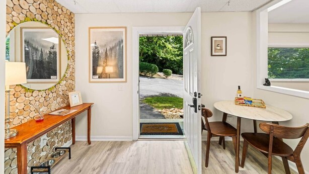 A hallway with a stone wall, wooden bench, framed artwork, and a door leading to a garden. - Pigeon Forge Getaway Near Dollywood / LeConte / The Island (Pigeon Forge)
