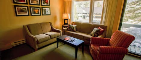 A living room with a sofa, armchair, coffee table, and a lamp.