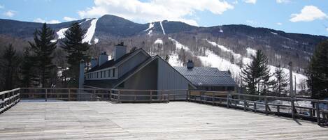 A wooden deck with a view of a mountain and a building in the background.