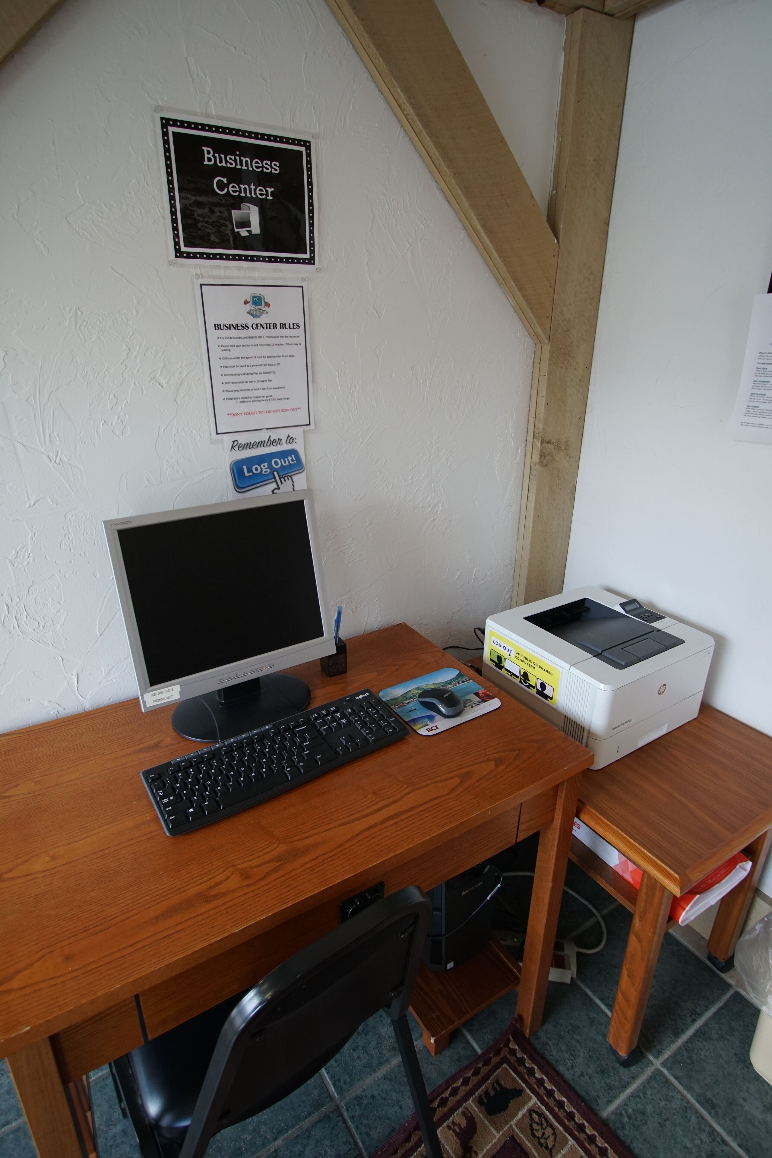 Ein Schreibtisch im Business-Center mit Computer, Drucker und einem Schild mit den Nutzungsbestimmungen.