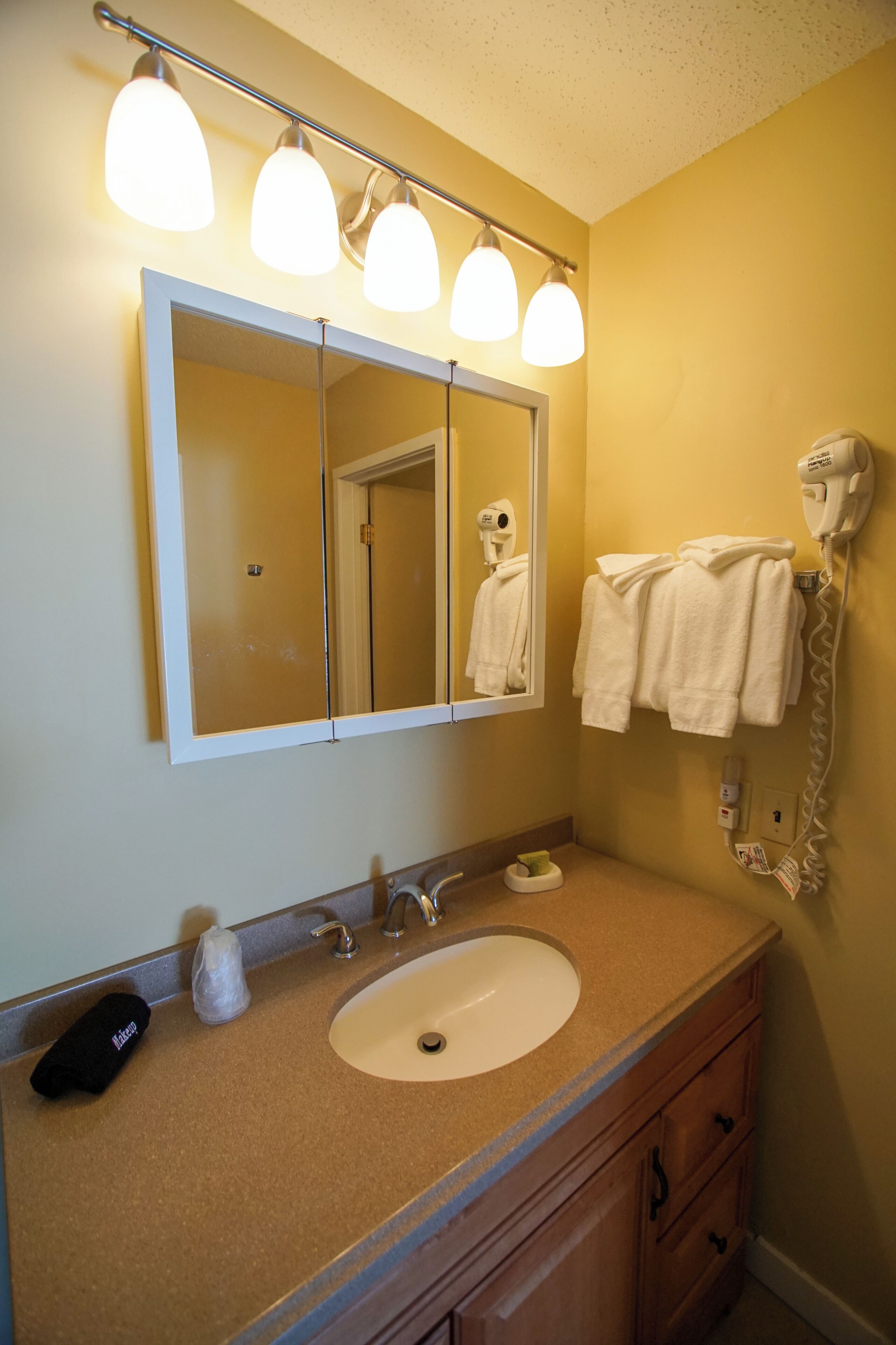 A bathroom with a sink, mirror, towel rack, and hairdryer.