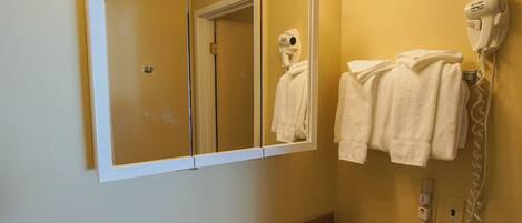 A bathroom with a sink, mirror, towel rack, and hairdryer.