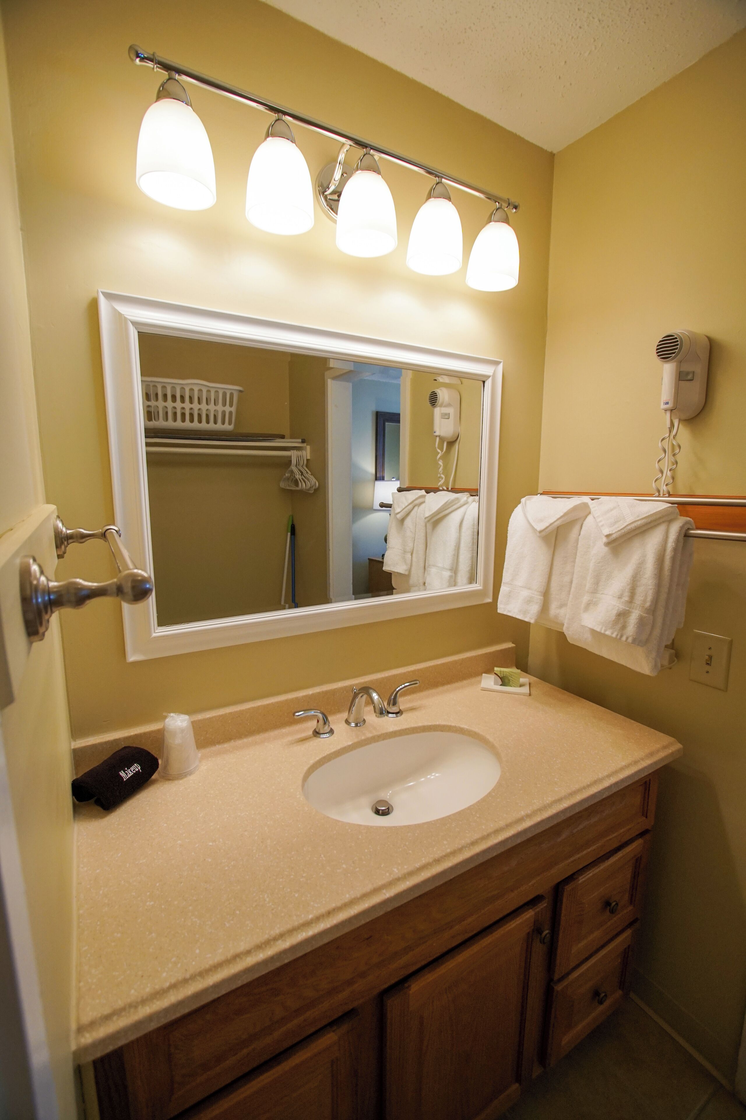 A bathroom with a sink, mirror, towel rack, and hair dryer.