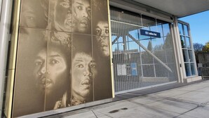 A modern building facade with a large glass window and a metal mesh screen. - Judkins Park Light Rail Townhouse Haven (Seattle)
