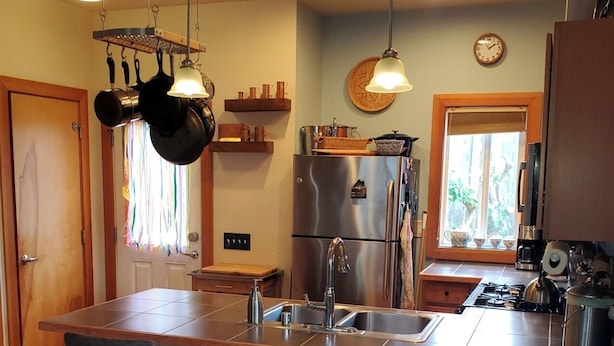 A modern kitchen with a central island, stainless steel appliances, and pendant lighting. - Judkins Park Light Rail Townhouse Haven (Seattle)