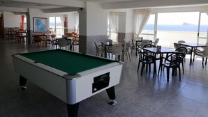 A pool table in a room with dining tables and chairs, large windows, and a view of the sea. - Apartamentos Beni Beach (Benidorm)
