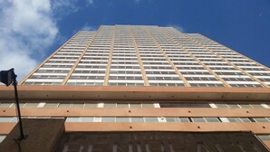 A tall building with a prominent 'BENEFICIAL' sign on the lower facade. - Apartamentos Beni Beach (Benidorm)
