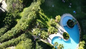 An aerial view of a resort with a central swimming pool, surrounded by lush greenery and palm trees. - Apartamentos Beni Beach (Benidorm)