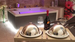 Een eettafel gedekt met borden, bestek, een wijnglas en een champagnefles.