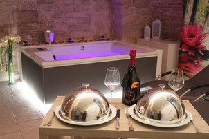 A dining setup with a table, plates, cutlery, a wine glass, and a bottle of champagne.