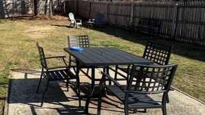 A patio with a table and chairs, a concrete floor, and a wooden fence in the background. - Comfy, private one Bedroom Apartment with full kitchen, living room, full bath. (Ridge)