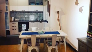 Een kleine keuken met witte kastjes, een inbouwmagnetron en een betegelde spatwand.
