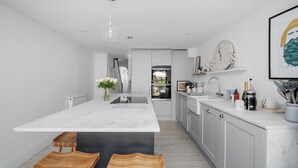 A modern kitchen with a large island, white cabinetry, and a marble countertop. - Bay View Luxury Stays - Iris Boutique Harbour Cottage, walking distance to Beach (Weymouth)