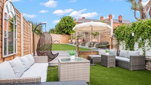A patio with wicker furniture, a glass table, and a white umbrella. - Bay View Luxury Stays - Iris Boutique Harbour Cottage, walking distance to Beach (Weymouth)