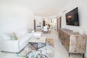 Un salon moderne avec un canapé blanc, une table basse et un téléviseur fixé au mur.