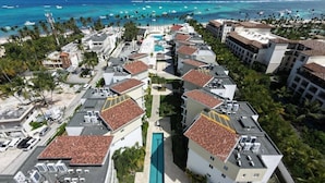 Ein Resort mit mehreren Gebäuden, einem zentralen Pool und Blick auf den Strand.