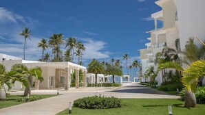 A resort with a central pathway, palm trees, and modern buildings. - Luxury 3BR beachfront Condo in Punta Cana (Punta Cana)