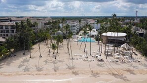 A resort with a pool, palm trees, and beachfront. - Luxury 3BR Beachfront Condo in Punta Cana (Punta Cana)