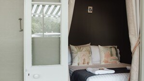 Un dormitorio con cama, almohadas y una ventana.
