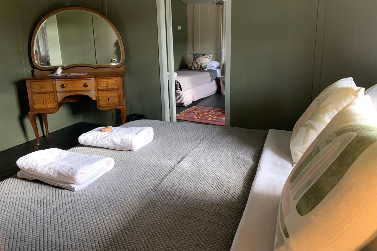 Ein Hotelzimmer mit einem Bett, einem Holzschrank, einem Spiegel und einer Tür zu einem weiteren Raum.